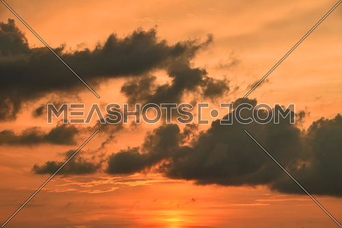 Beautiful dramatic orange sunset cloudscape with fluffy clouds over clear sky, low angle view