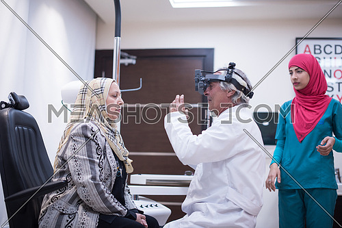 Middle Eastern Ophthalmologist examing cornea of senior woman with slit lamp in the modern clinic