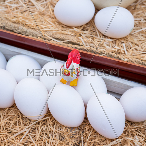 White chicken eggs leaning on straw in wooden basket,close up.