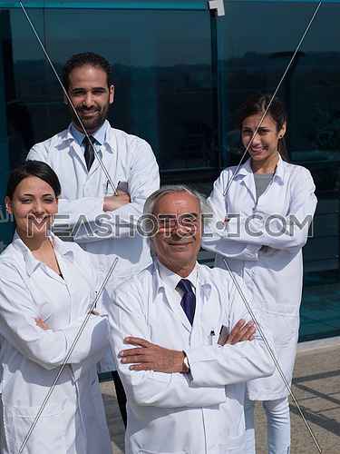 smiling team of doctors in front of modern hospital