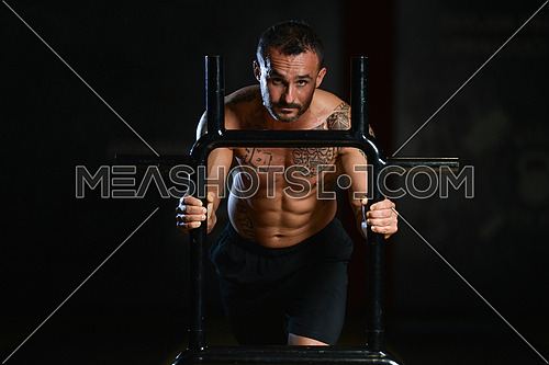Muscular Man Doing Heavy Weight Exercise Weighted Speed Sled In Gym