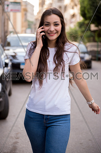 A young woman walking on the street talking in the mobile phone
