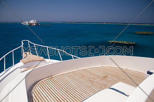 the front of a live a board marine vessel boat showing the wooden deck and the sea
