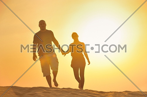 relaxed young pasionate couple enjoying the sunset  beauty on their honeymoon, on a desert with orange background