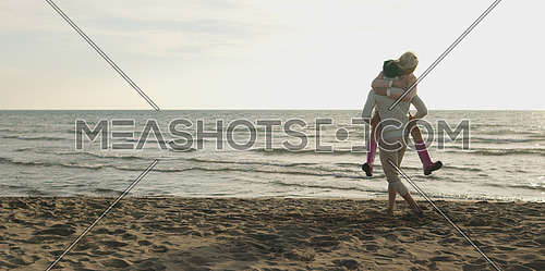 Young couple having fun on beach during autumn sunny day