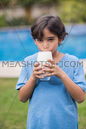 Middle Eastern boy enjoying with a glass of milk in his hand outside on summer day