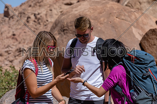 mid shot for a group of tourists wearing backpacks standing and talking while exploring Sinai Mountain for wadi Freij at day.