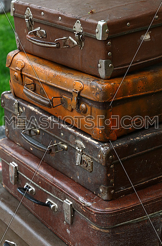 Stack of four old vintage antique grunge travel luggage brown leather suitcase trunks, close up, high angle side view