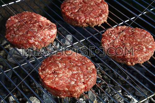 Close up raw beef or pork meat barbecue burgers for hamburger cooked grilled on bbq grill, high angle view