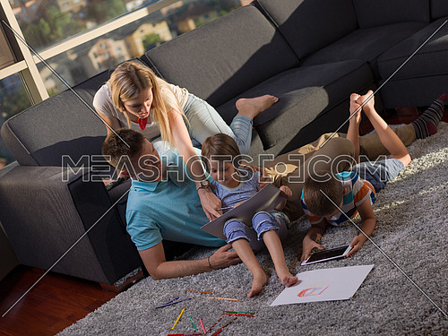 Happy Young Family Playing Together at home using a tablet and a children's drawing set