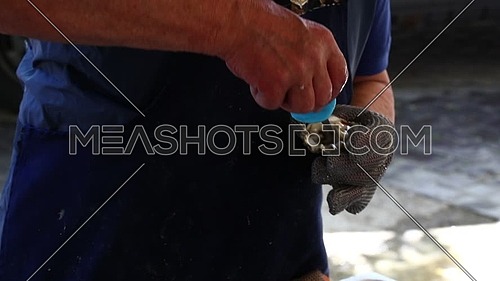 Man selling and opening fresh oysters with knife wearing protective metal gloves, at fishermen seafood market close up, personal perspective