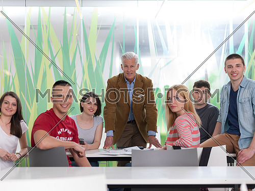 portrait of confident teacher in school classroom,  students group on class in background
