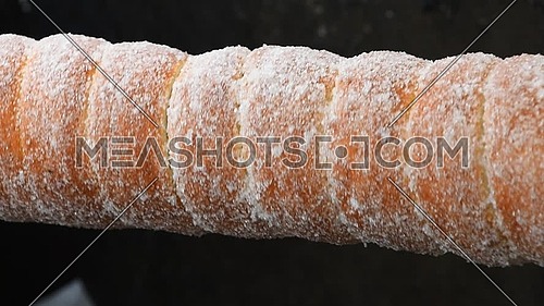 Close up sweet Trdelnik baking on grill and rolling, this spit cake is popular in Europe, Austria, Hungary, Slovakia and Czech, especially in Prague