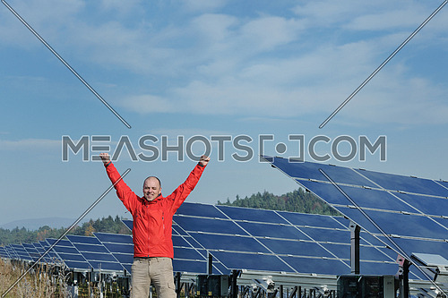 Male engineer at work place, solar panels plant industy in background