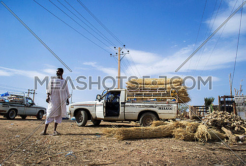 A sudanese driver standing beside his pick up ready to transport hay