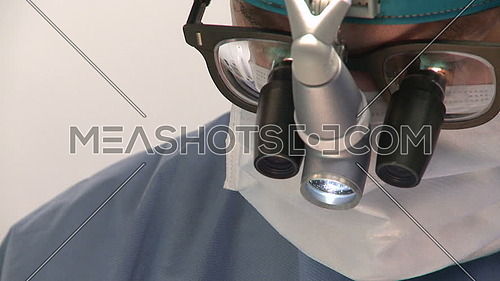 Closeup of surgeon's face wearing magnifying glass during surgery 
