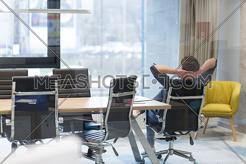 A time for relax. Young tired casual businessman relaxing at the desk in his office
