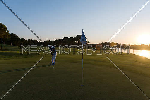 golf player hitting ball  with driver on course at beautiful sunset