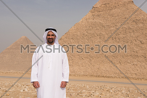 young man as tourist  wearing  arabian traditional clothes in egypt with giza pyramids in background