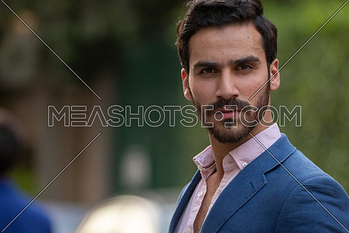 Mid-shot an elegant man walking in the the street in formal suit in blue at day