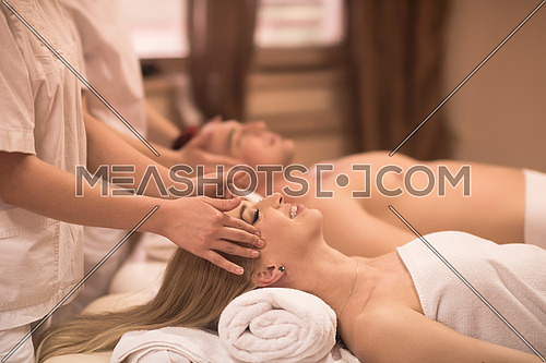 happy young beautiful couple enjoying head massage at the spa