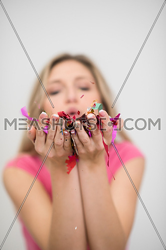 beautiful young woman celebrating new year and chrismas party while blowing confetti decorations to camera