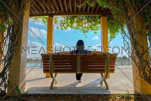 A girl sitting on a bench shot from the back