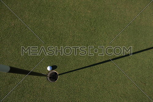 top view of golf ball on edge of course hole representing achivement and success business concept