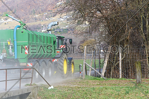 Agricultural tractor pulling a trailer on a farm road