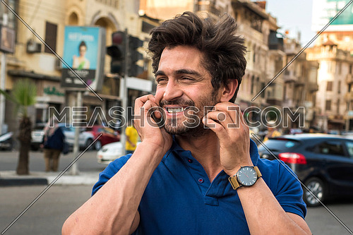 close up young man talking in mobile phone in the street in korba area at day