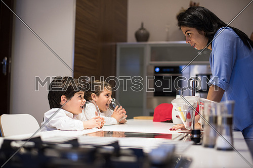 little middle east boy and girl with mom eating snacks and drinking milk in the kitchen with pleasure