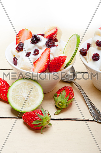 fruit and yogurt salad healthy breakfast over white wood table