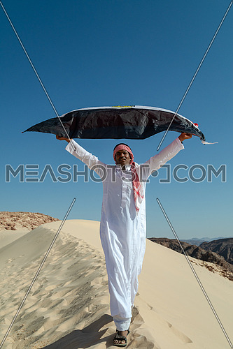 Bedouin man holding Egyptian Flag in Sinai Trail from Ain Hodouda at day.