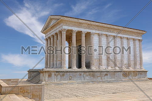 Side view of Maison Carree (square house), ancient building in Nimes, Provence, southern France, one of the best preserved antique Roman temples, historical building,over clear blue sky