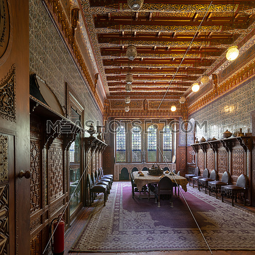 Manial Palace of Prince Mohammed Ali. Dining room at the Residence Building, with ornate wall and ceiling, Big ornate window, built-in wooden decorated cupboards and ornate carpet, Cairo, Egypt
