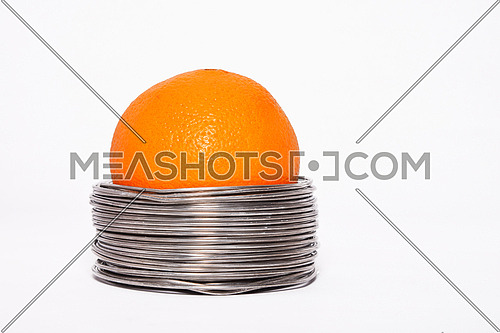 Wired orange: whole orange in coils of aluminium wire isolated on white background