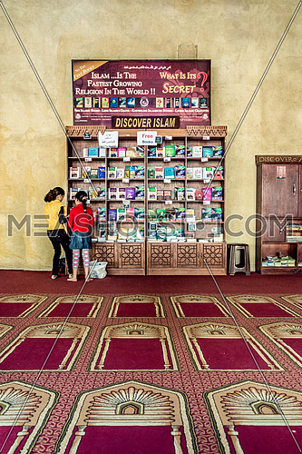 two girls  standing looking towards the Discover Islam free book section for tourists