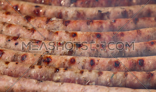 Close up cooking meat sausages on grill, smoking and broiling them, high angle view