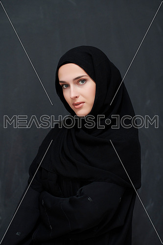 Modern young muslim woman in black abaya. Arab girl wearing traditional clothes and posing in front of black chalkboard. Representing modern and rich arabic lifestyle