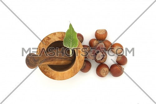 Fresh raw hazelnuts and wooden rustic-style mortar and pestle top view isolated on white background