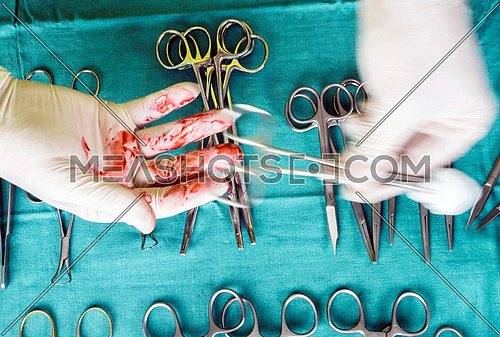 Surgeon working in operating room, hands with gloves holding scissors sutures, conceptual image, composicon horizontal