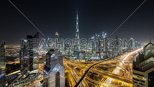 Extreme long shot for Dubai City showing Burj Khalifa and skyscrapers and traffic at night.