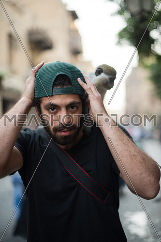 Portrait of a young middle eastern tourists who enjoy with a monkey on his shoulder