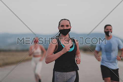 Multiethnic runners group wear face masks running keep social distance outdoor. Fit healthy diverse team wears sportswear jogging in the evening on nature sports track distancing for safety.