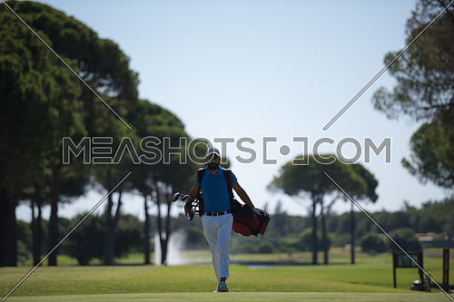 handsome middle eastern golf player carrying  bag  and walking at course to next hole
