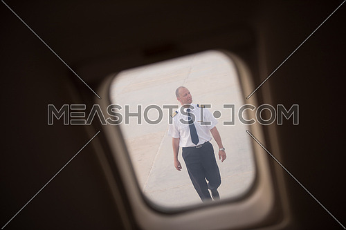 Young middle eastern successful pilot walking towards private jet