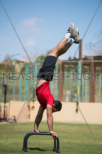 young middle eastern athletic man workout handstand outside on a sunny day