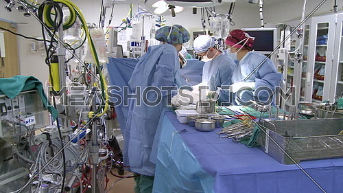 Pan Right long shot of operating room while medical team performing surgery