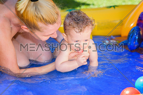 Mother and son play in a small paddling pool
