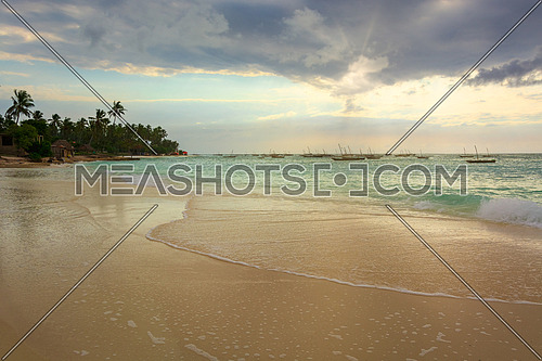 A nice beach with Several fishing boats anchored at sunset with sunbeams.Zanzibar coast,Tanzania.